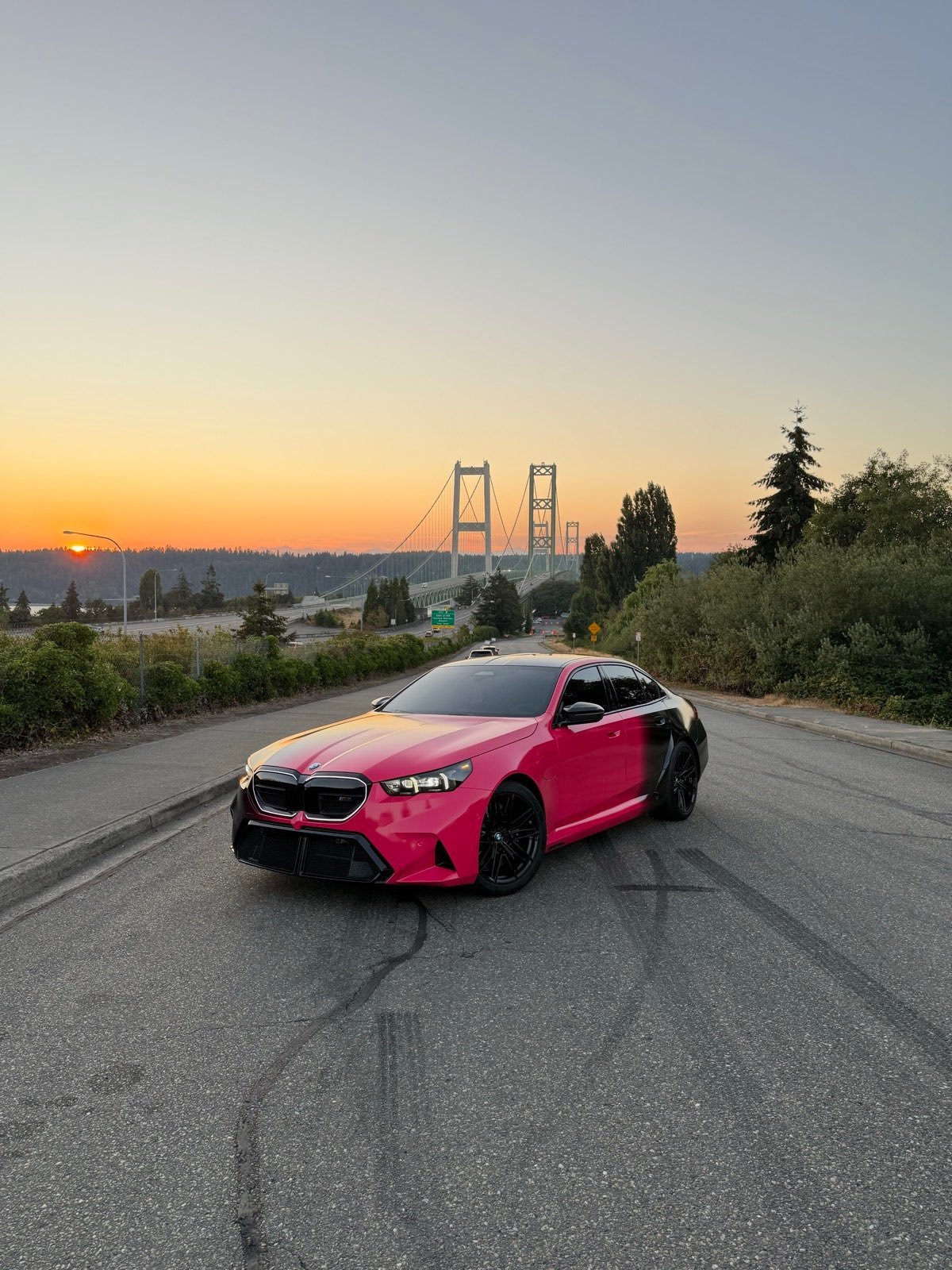 BMW M5 wrapped in pink and black vinyl by Wraptik, at sunset by the Tacoma Narrows Bridge